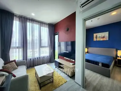 Modern apartment living room with large windows and adjacent bedroom, featuring stylish decor and natural light.