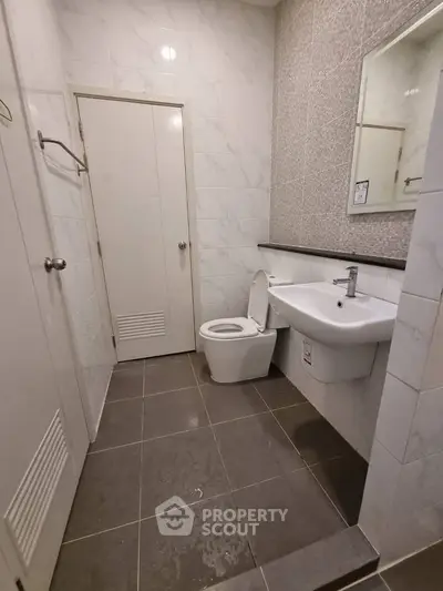 Modern bathroom with sleek design featuring a wall-mounted sink and tiled walls.