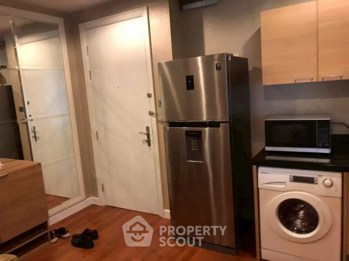 Modern kitchen with stainless steel fridge, washing machine, and microwave