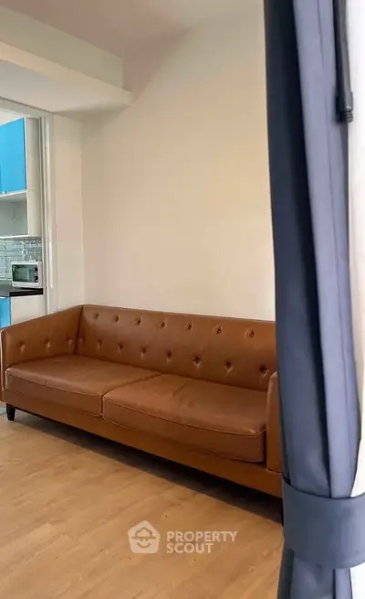 Modern living room with stylish brown leather sofa and open kitchen view.