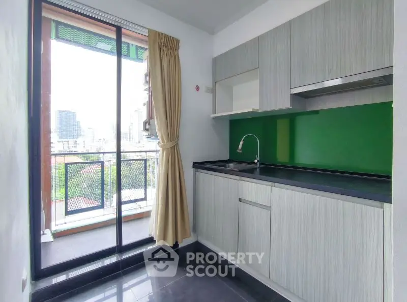 Modern kitchen with sleek cabinets and balcony view in urban apartment.