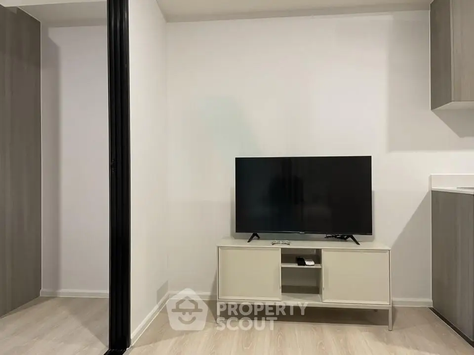 Modern living room with sleek TV stand and flat-screen TV, featuring minimalist design and neutral tones.