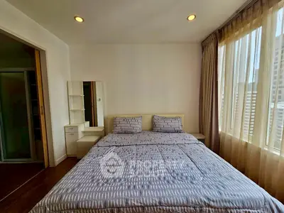 Spacious bedroom with large windows and modern decor in a high-rise apartment.