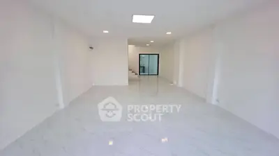 Spacious modern living room with sleek white flooring and ample natural light.