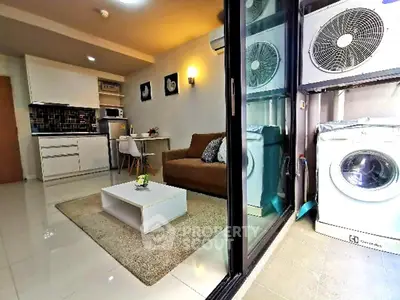 Modern living room with open kitchen and laundry area, featuring sleek appliances and cozy decor.