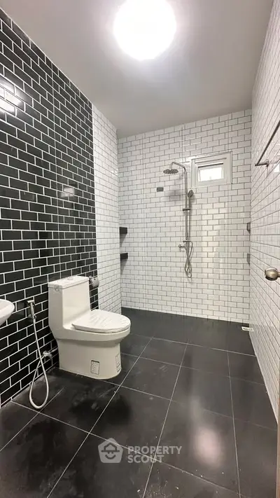 Modern bathroom with sleek black and white tile design and contemporary fixtures.