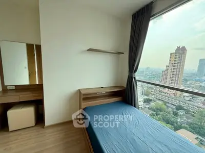 Modern bedroom with city view, featuring sleek furniture and large window for natural light.