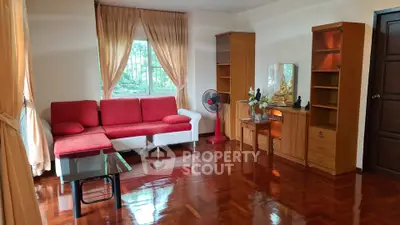Spacious living room with red sofa and wooden flooring, perfect for relaxation.