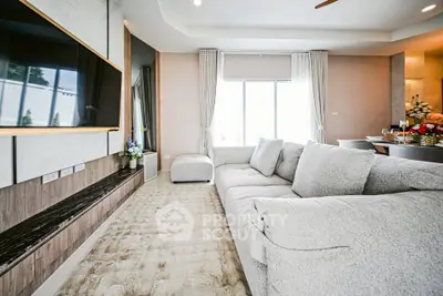 Spacious modern living room with plush sofa and large TV, perfect for relaxation and entertainment.