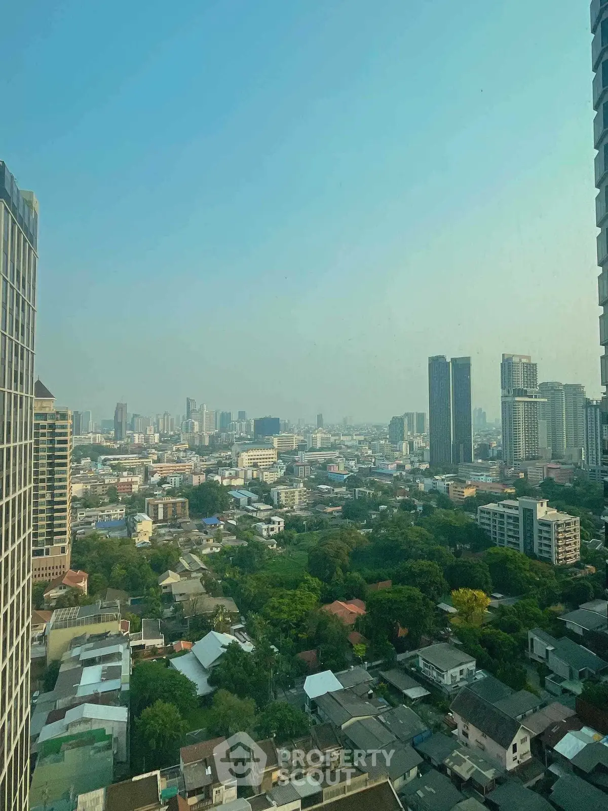 Stunning cityscape view from high-rise building showcasing urban skyline and lush greenery.