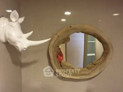 Unique bathroom decor with rhino head sculpture and rustic wooden mirror frame.