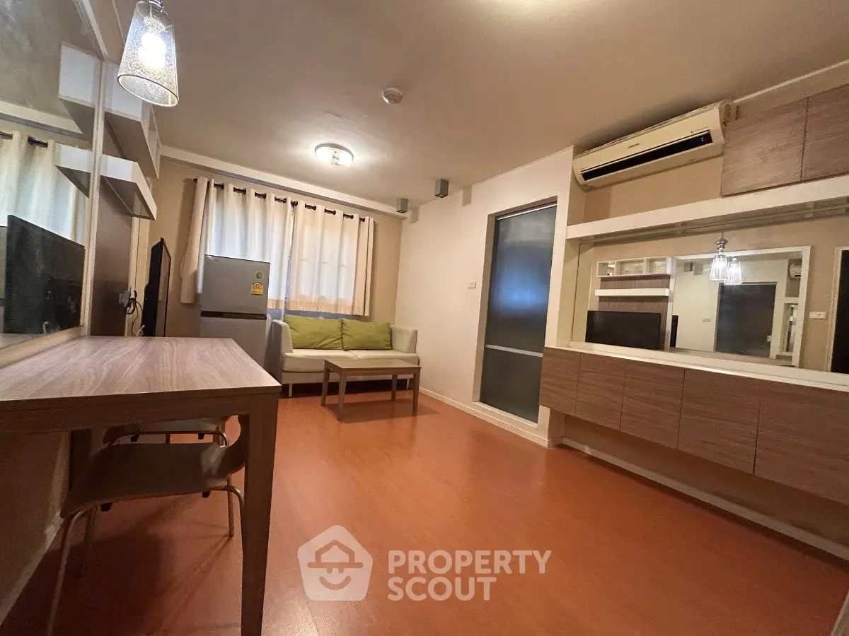 Modern living room with wooden flooring, cozy seating, and air conditioning in a stylish apartment.