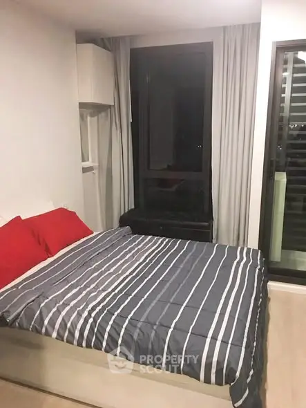 Modern bedroom with large window and stylish bedding in a contemporary apartment.