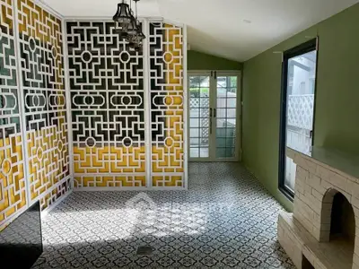 Charming interior with decorative wall panel and patterned tile flooring, featuring a cozy fireplace and ample natural light.