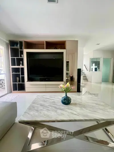 Modern living room with sleek marble table and large TV unit, perfect for stylish entertainment.