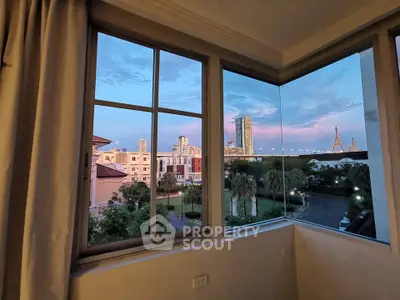 Stunning cityscape view from a modern apartment window at sunset, showcasing urban skyline and serene surroundings.