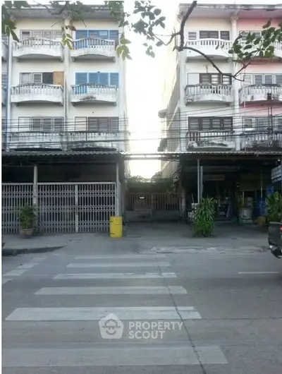 Street view of residential buildings with balconies and gated entrances.