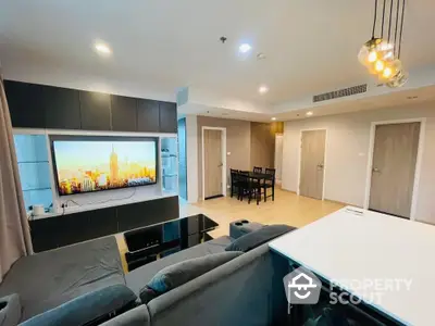 Spacious modern living room with sleek furniture and large TV, perfect for relaxation and entertainment.