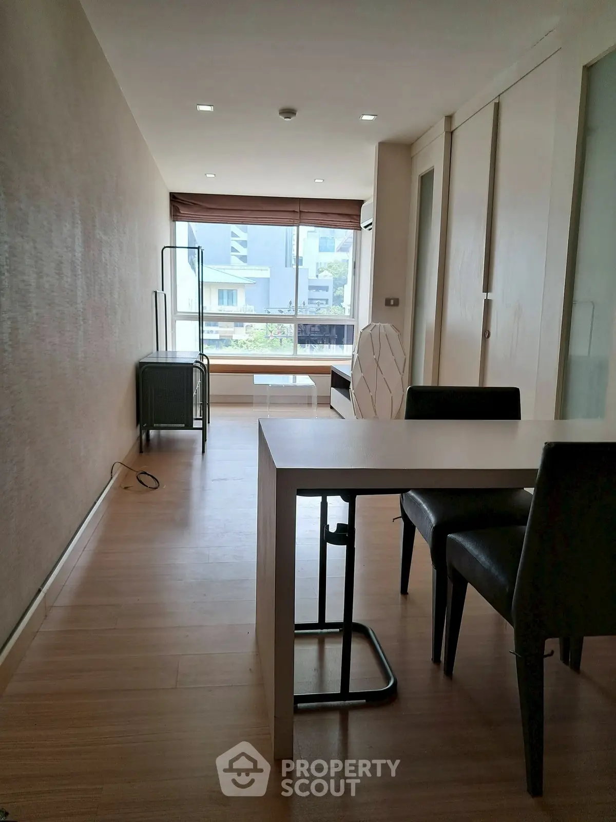 Modern living room with sleek furniture and large window offering natural light.