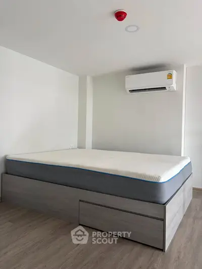 Modern bedroom with sleek bed frame and air conditioning unit, perfect for comfortable living.