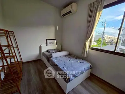 Cozy bedroom with single bed and air conditioning, featuring a large window with a view.