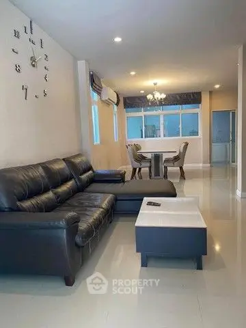 Spacious living room with modern leather sofa and dining area in open layout.
