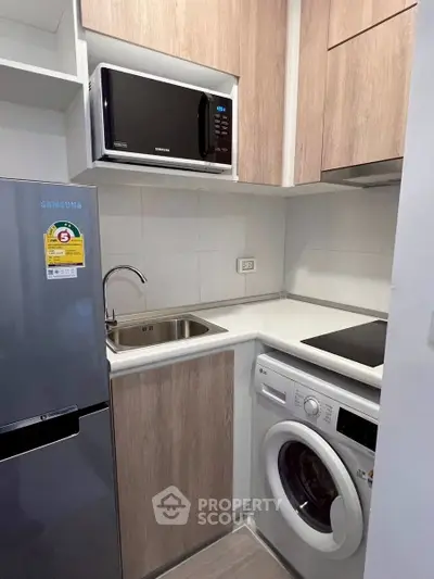 Compact modern kitchen with appliances including fridge, microwave, and washing machine.