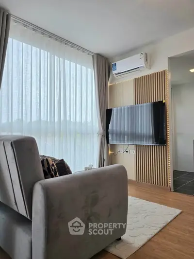 Modern living room with large window, stylish decor, and mounted TV