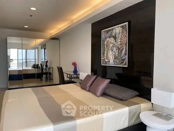 Luxurious bedroom with mirrored wardrobe and elegant decor in modern apartment.