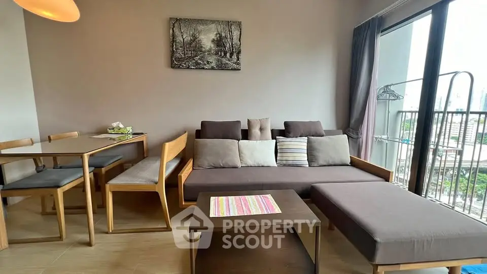 Modern living room with stylish furniture and large window offering city views.