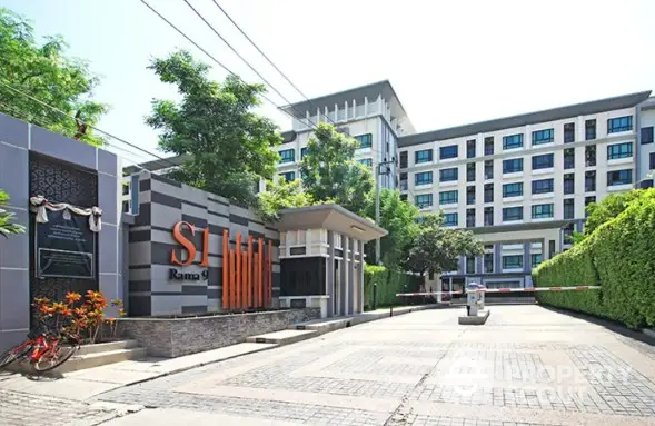 Modern condominium entrance with lush greenery and stylish architecture