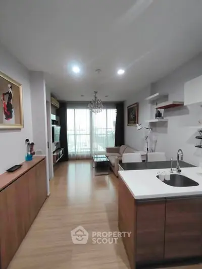 Modern open-plan living room with kitchen, featuring stylish decor and ample natural light.