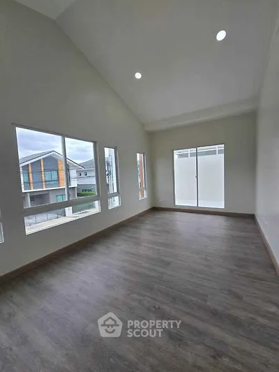 Spacious modern room with large windows and high ceiling, perfect for natural light.