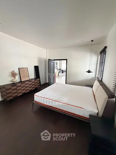 Spacious bedroom with modern decor and large windows for natural light.
