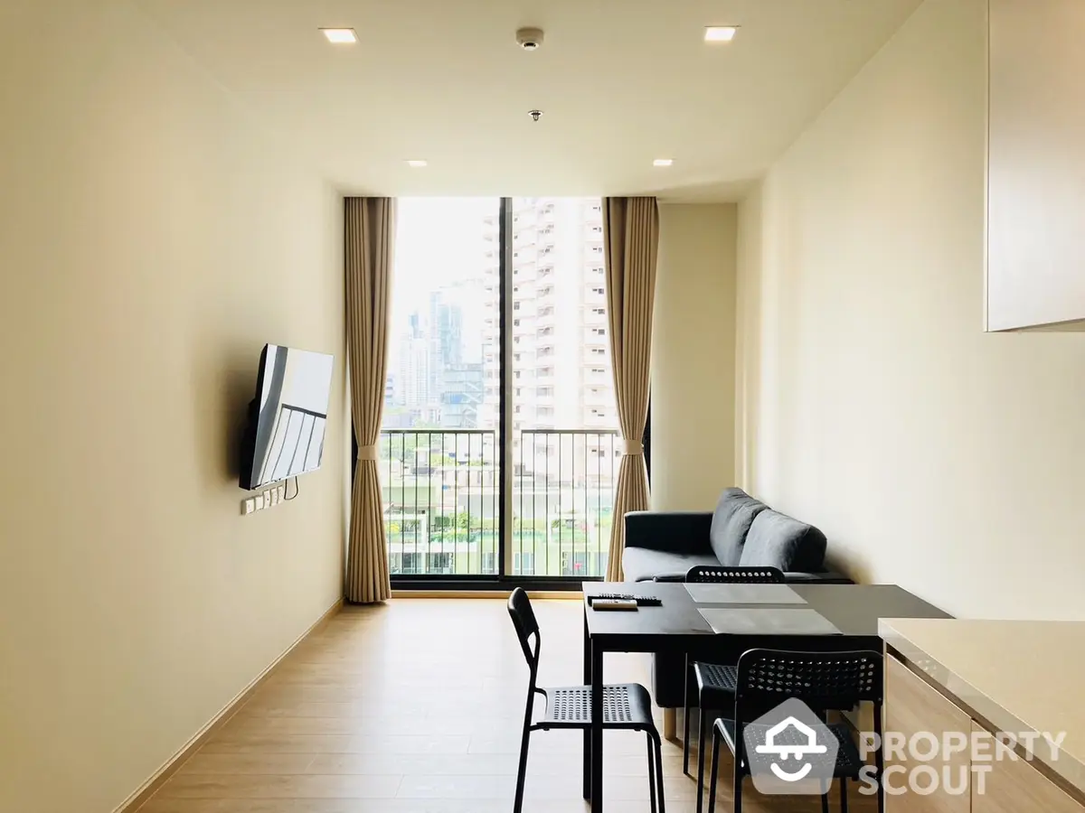 Modern minimalist living room with ample natural light, sleek furniture, and a balcony offering an urban view, perfect for a comfortable city lifestyle.