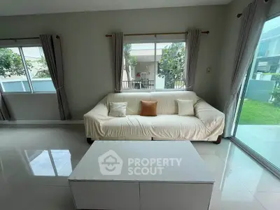 Spacious living room with modern sofa and large windows overlooking garden