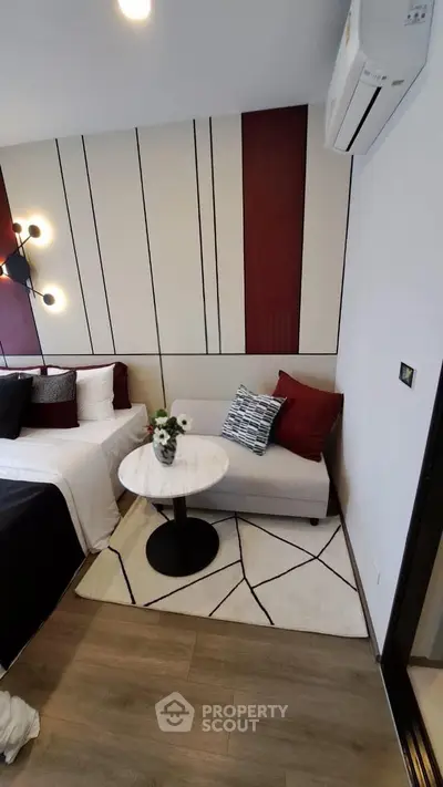 Modern bedroom with stylish decor, featuring a cozy seating area and elegant lighting.