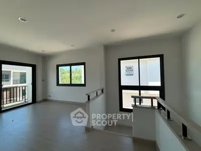 Spacious modern living room with large windows and wooden flooring, perfect for natural light lovers.