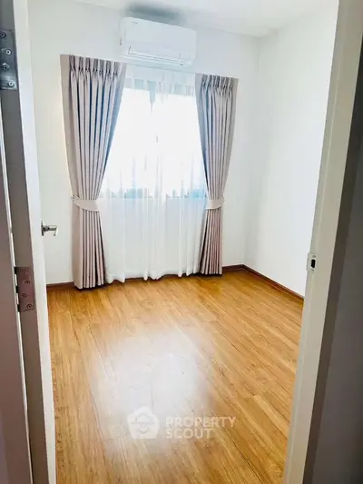 Bright empty room with wooden flooring and air conditioning