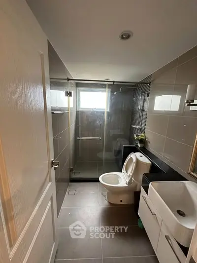 Modern bathroom with sleek design, featuring a glass shower enclosure and contemporary fixtures.