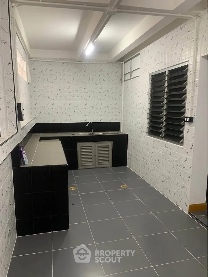 Spacious kitchen with modern black and white tile design and ample counter space.