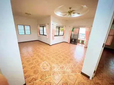 Spacious living room with tiled flooring and large windows for natural light.