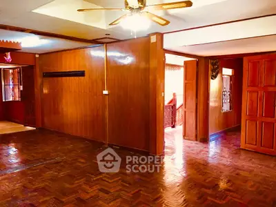 Spacious wooden interior with parquet flooring and ceiling fan in a cozy living area.
