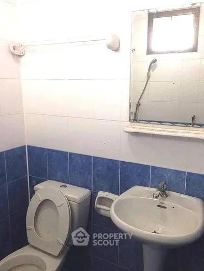 Compact bathroom with blue and white tiles, featuring a toilet and sink.