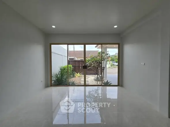 Spacious room with large glass doors opening to a garden view, perfect for natural light.