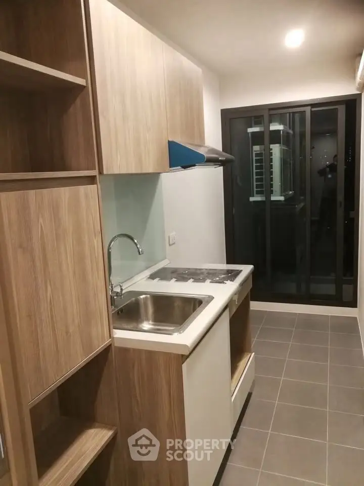 Modern kitchen with sleek cabinetry and sliding glass doors leading to a balcony.
