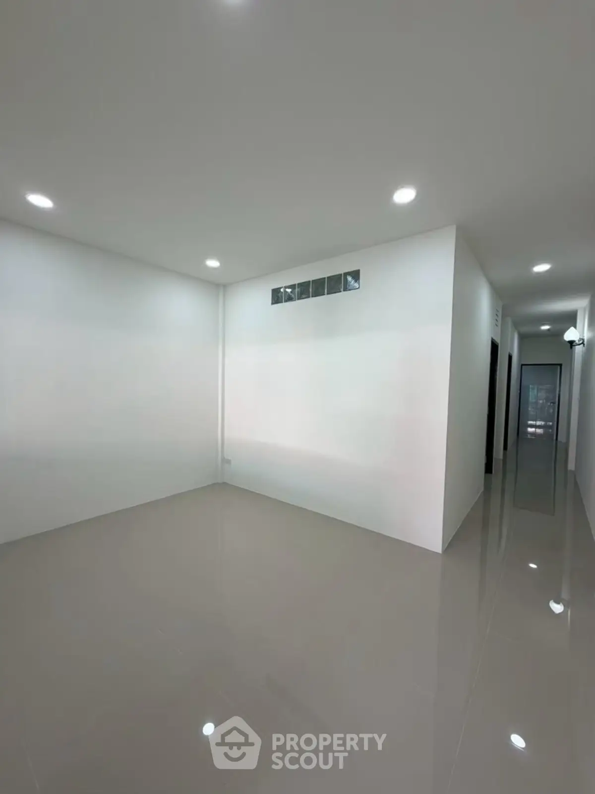 Spacious empty room with glossy tiled floors and recessed lighting, perfect for customization.