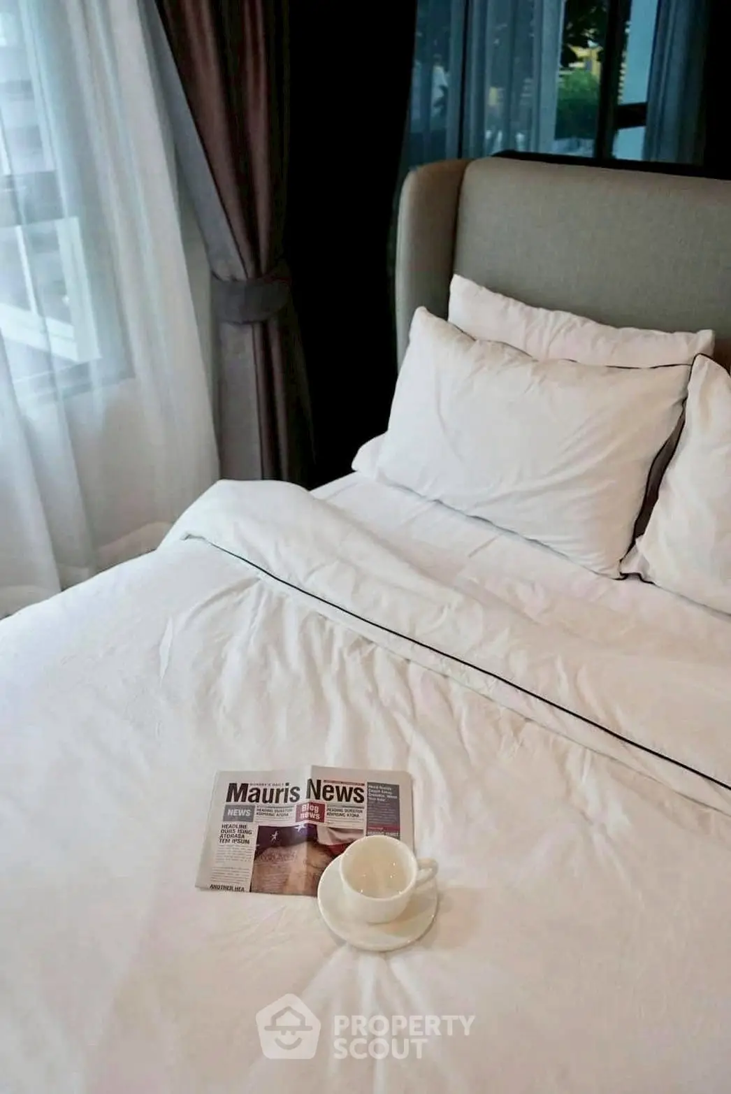 Cozy bedroom with elegant bedding and a cup of coffee on the bed, perfect for relaxation.