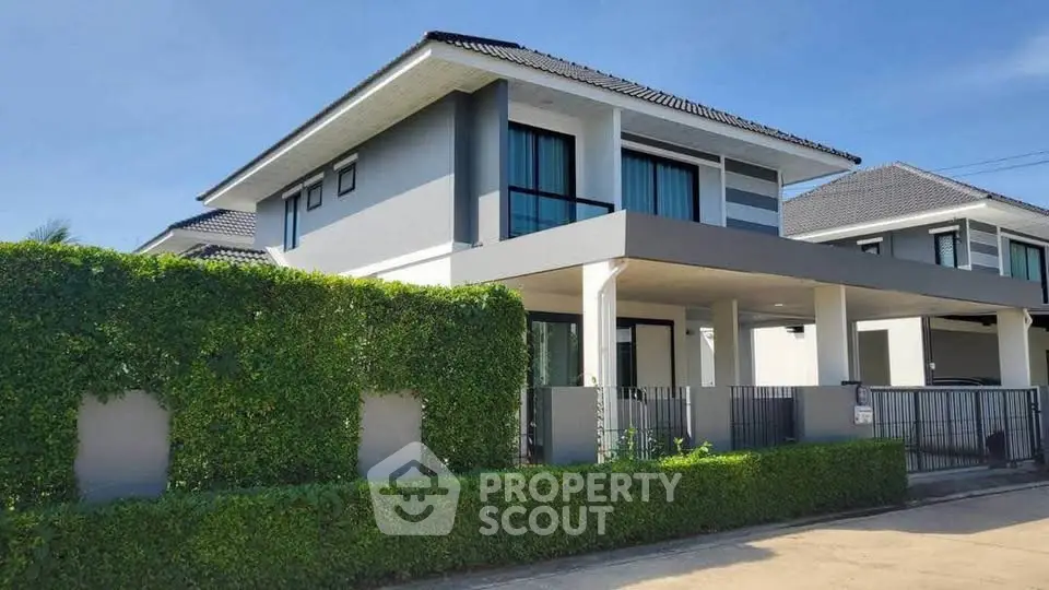 Modern two-story house with sleek design and lush green hedges