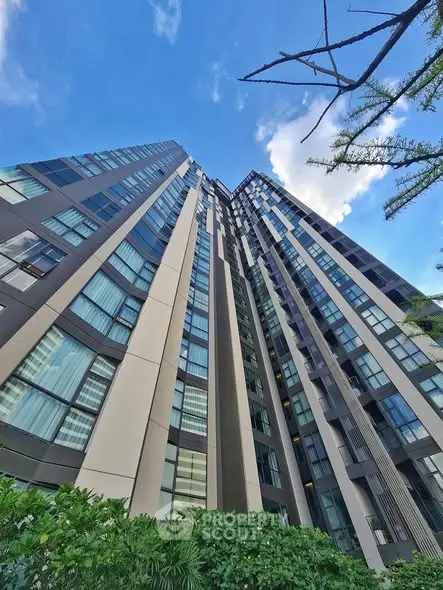 Modern high-rise building with sleek design and large windows against blue sky.